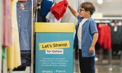 A child drops used clothing items into a ‘shwop’ box at a branch of Marks & Spencer.