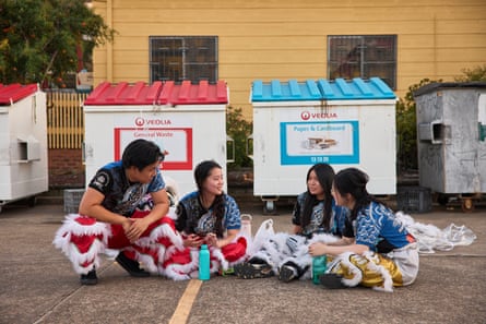 Dancers sit on the ground of the concrete car park as they take a break during rehearsals