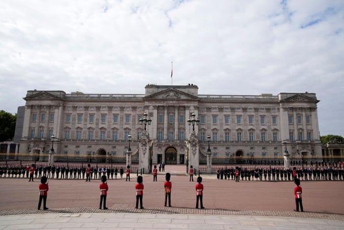 King's Guard soldiers and household staff stand outside Buckingham Palace waiting for the Queen’s coffin.