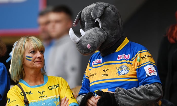 A fan of Leeds Rhinos stands with a fellow fan, wearing a Rhino costume.