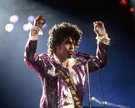 Prince performing onstage during the 1984 Purple Rain tour in Detroit, singing with his hands in the air