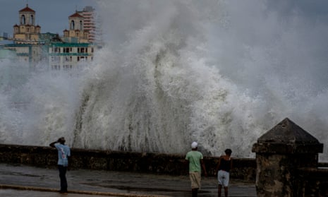 People stand along a waterfront as huge waves crash against a seawall in the wake of Hurricane Ian in Havana, Cuba, on 28 September 2022.