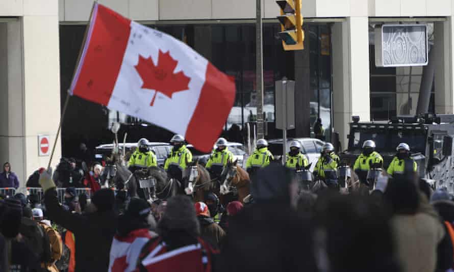 La policía montada y un vehículo policial blindado se colocan frente a los manifestantes durante las protestas del viernes en Ottawa.