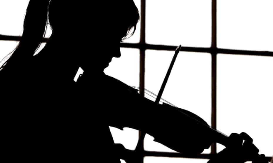 A musician playing the violin in silhouette.