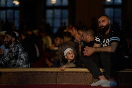 A child looks at a man inside a mosque filled with worshippers.