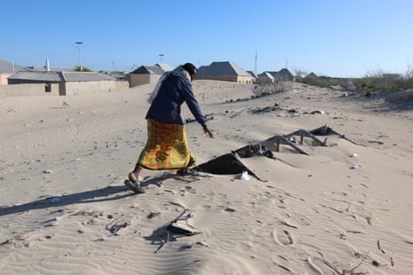 A man pointing out visible apex of the roof of a submerged building in Hobyo