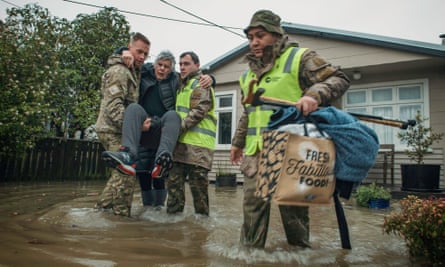 New Zealand defence force help a resident evacuate in Buller district in July.