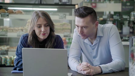 A woman and a worried looking man stare at a laptop screen.