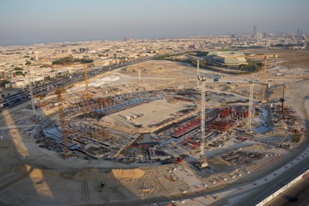 A building site with cranes and the outline of a stadium