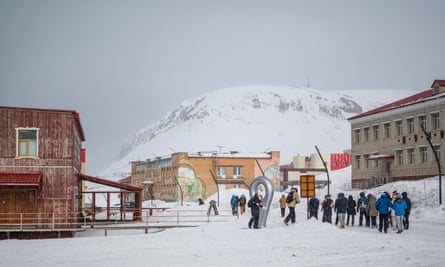 سياح يسيرون على الثلج أثناء زيارتهم لمدينة عمال المناجم بارنتسبورج، الواقعة في أرخبيل سفالبارد، شمال النرويج.