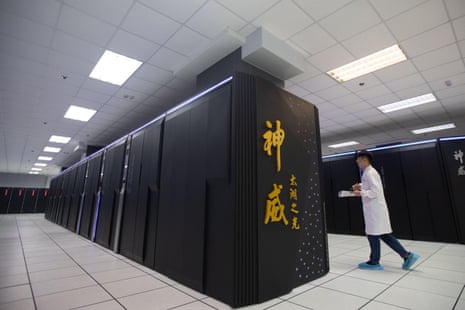 A person in a white lab coat walks past the a supercomputer with gold Chinese characters