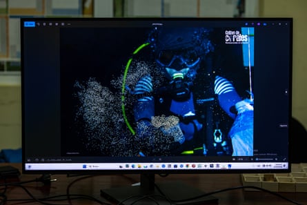An image on a screen shows egg and sperm collection in the coral farm in front of the National Aquarium