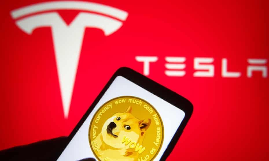Dogecoin logo of a cryptocurrency seen displayed on a smartphone with a Tesla logo in the background