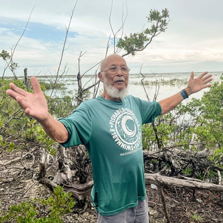 Man in green T-shirt spreads his arms by the waterside