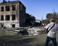 A man photographs a crater at the site of a Russian missile impact in Ukraine.