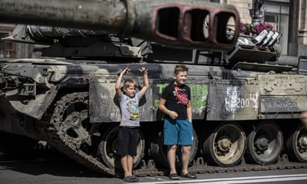 Ukrainian children pose with a Russian tank captured by Ukrainian forces in Kyiv.