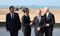 The UK foreign secretary, David Cameron, left, looks on as France's president, Emmanuel Macron, the German chancellor, Olaf Scholz, and the US president, Joe Biden, talk. A beach is in the background.