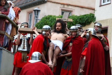 Image 22: Actors dressed as Roman soldiers carry another dressed as Jesus Christ on the cross