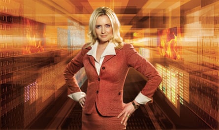 Julie Meyer in a publicity shot, wearing a rust-coloured skirt and blazer, and a cream blouse, standing with her hands on her hips, in front of blurred golden graphics
