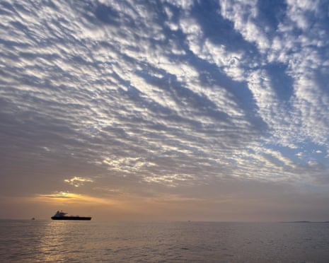 The sun rises behind a tanker anchored in the strait of Hormuz off the coast of Qeshm Island, Iran