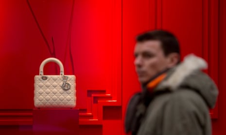 a man passes a red window with a white Dior on show