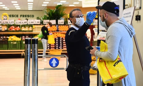 A worker checks the temperature of a customer at the entrance of a supermarket in Turin, Italy.