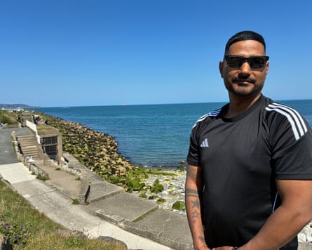 Bhandari wearing a T-shirt and sunglasses poses for a picture with the sea in the background