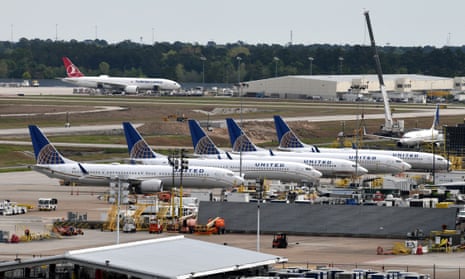 a row of blue and white planes sitting on a concrete area by an airport