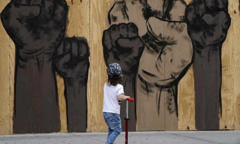 A child rides a scooter past a mural by artists Malik Crawford and Jerome Tiunayan on a boarded-up store in the Union Square section of New York on Monday.