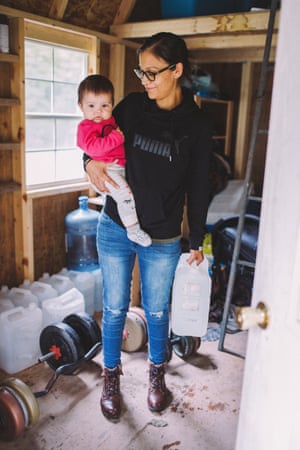 Lokarenhtha Thomas holds her daughter Waehsa Thomas and the water she needs to bring into her home.