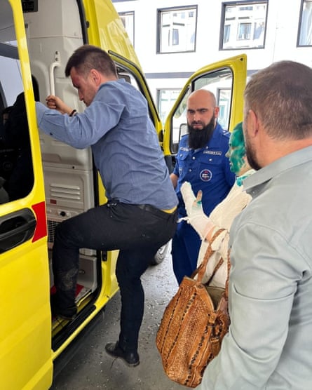 Alexander Nemov climbing into an ambulance with Elena Milashina waiting behind him.