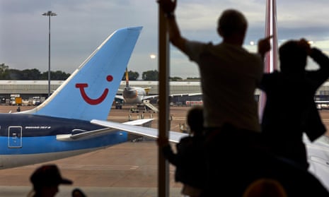 A TUI Airways Boeing 787-8 Dreamliner at Manchester Airport as a family view the runway from inside the terminal window.
