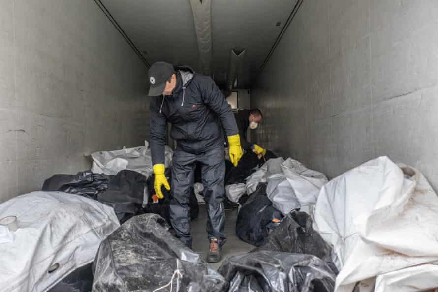 Morgue employees inside a truck storing bodies.