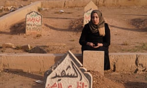 Woman next to the grave of her family who were victims in a coalition airstrike in March 2017 in the Iraqi city of Mosul. (Photograph: Ismael Adnan for the Guardian)