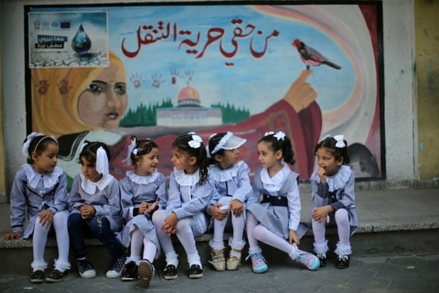 Palestinian schoolgirls sit in front of a mural on the first day of a new school year, at a United Nations-run school in Khan Younis in the southern Gaza Strip August 28, 2016