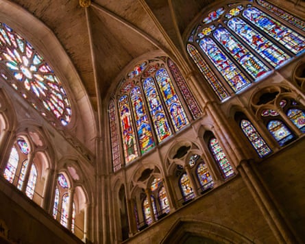 A view looking up into the corner of a cathedral where two walls of stained glass windows meet