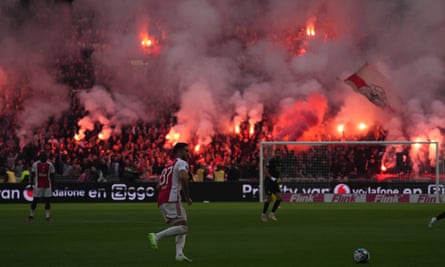 Ajax fans hold up flares during the game against Feyenoord before the match was suspended