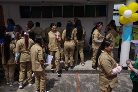 A group of women in brown uniforms stand around outside