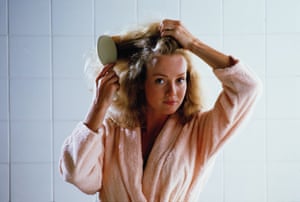 Woman in peach dressing gown brushing hair.