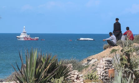 Palestinian men watch an Open Arms vessel approaching the coast off Gaza City on 15 March.