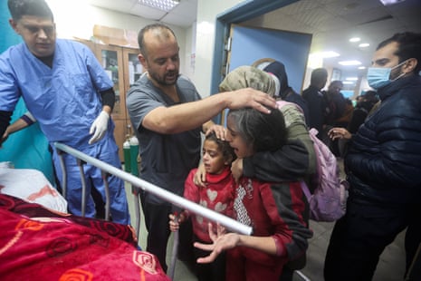 People stand by the bed of a person wounded in an Israeli strike at a hospital in Khan Younis