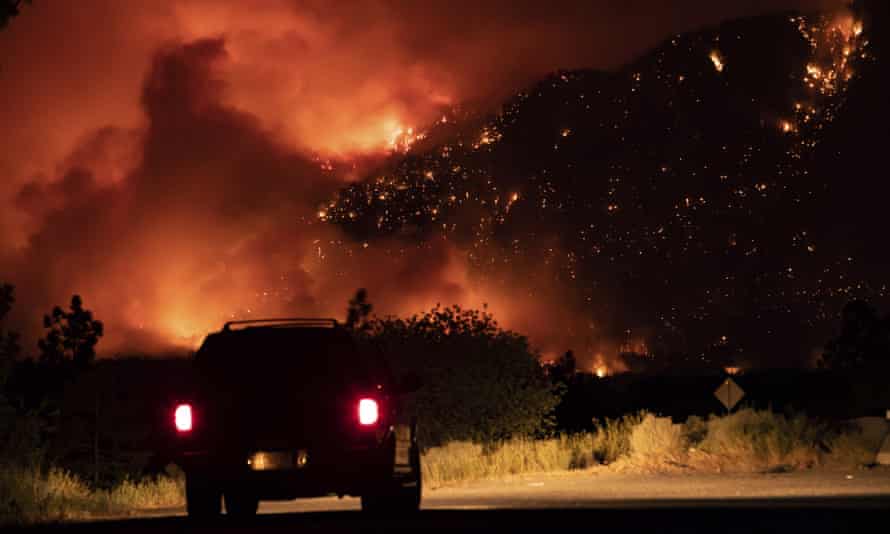 A motorist watches from a pullout on the Trans-Canada Highway as a wildfire burns on the side of a mountain in Lytton, British Columbia, on Thursday.