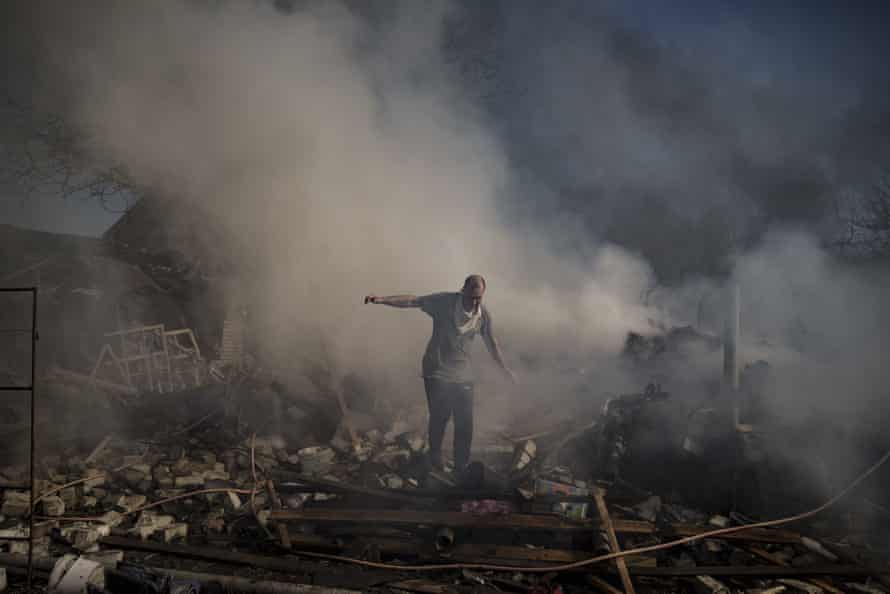 A man walks on the debris of a burning house, destroyed after a Russian attack in Kharkiv.