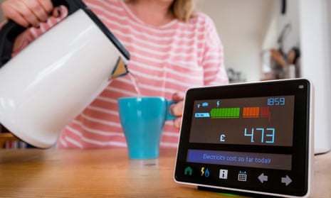 A woman making a cup of tea: next to her is a smart meter showing her energy on the kitchen counter