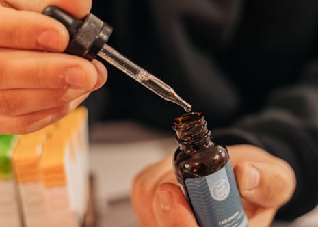 hands hold dropper over small bottle of cbd oil