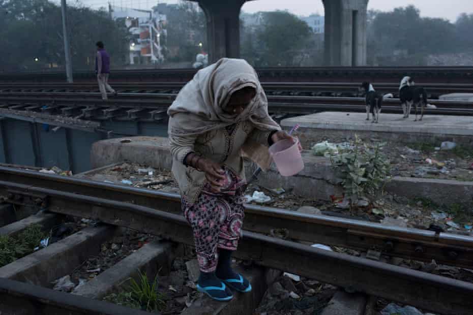 A woman looks for a place to defecate on the railroad tracks, early in the morning in the Anna Nagar slum, in Delhi