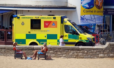 An ambulance drives along the promenade in Bournemouth on a hot day in July