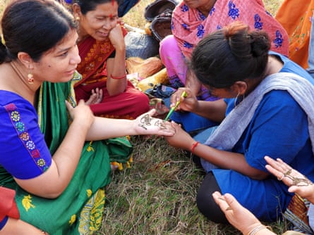 Mamoni Malakar, a Hargila Army member paints a henna tattoo of the hargila on Purnima Devi Barman’s palm.