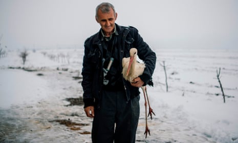 Safet Halil holds a stork in his farm backyard