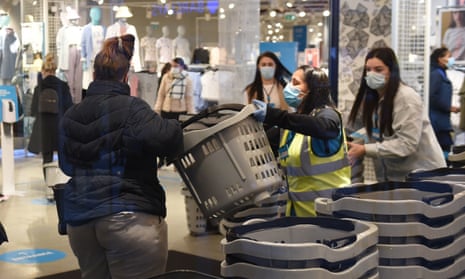 Early morning shoppers take a shopping basket from a member of staff as they enter the Primark store